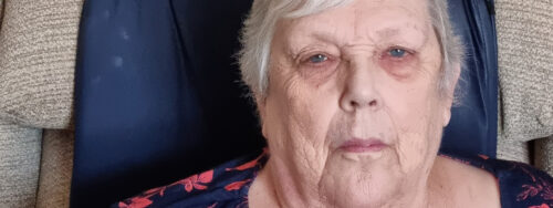 Elderly woman with a contemplative expression sitting in a chair