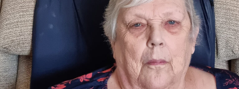 Elderly woman with a contemplative expression sitting in a chair