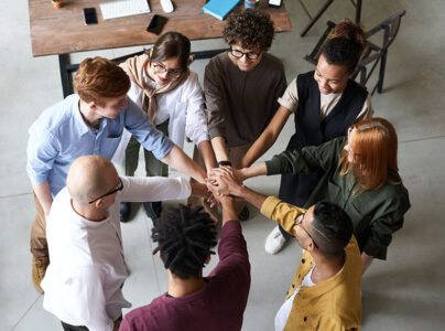 Diverse group of colleagues joining hands in a team-building exercise.