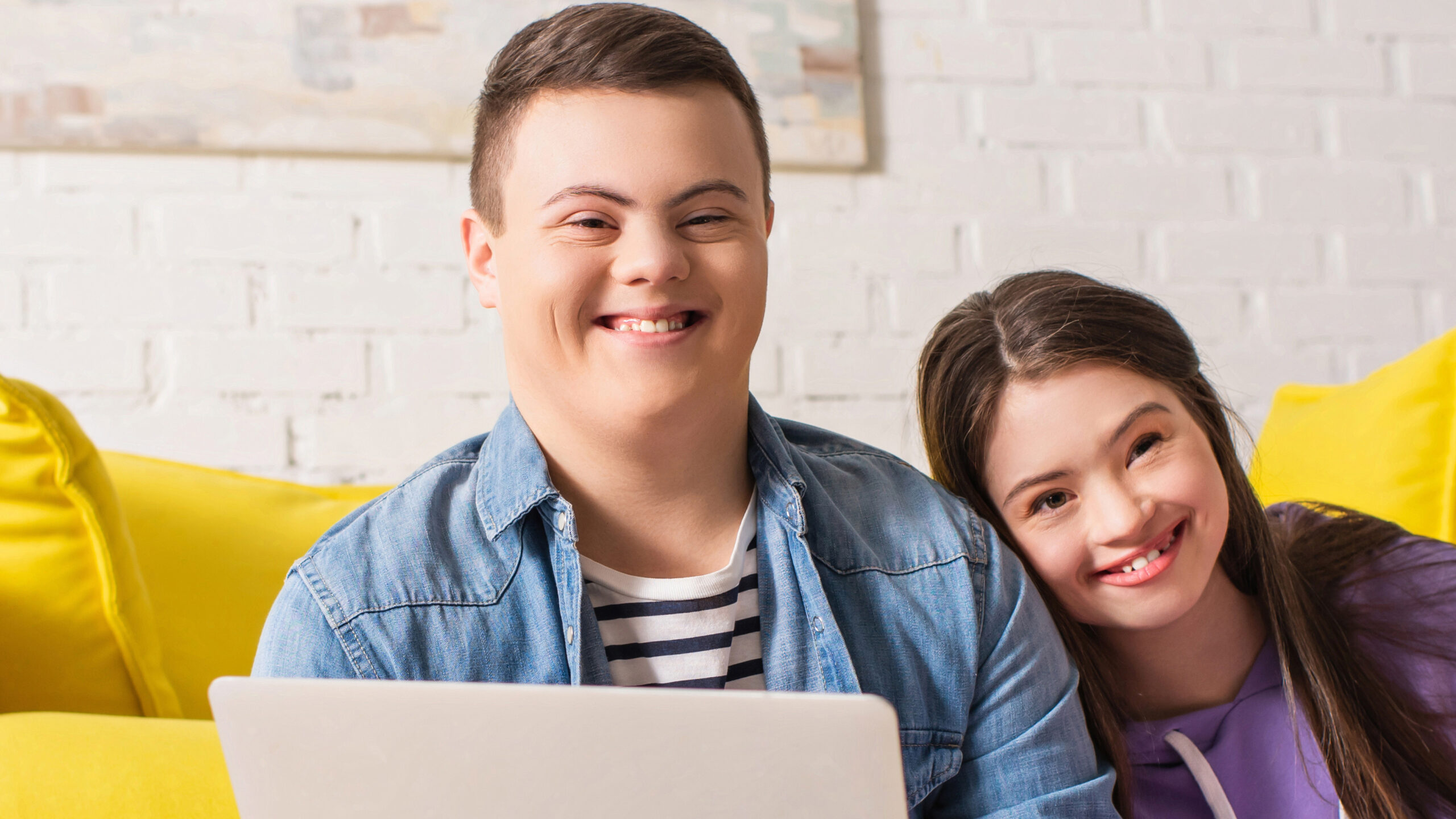 Smiling teen boy holding laptop near girlfriend with notebook at home, banner,stock image