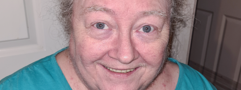 close-up portrait of an elderly woman smiling warmly in a teal top