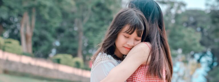 Young girl with a content smile embracing her mother in a park