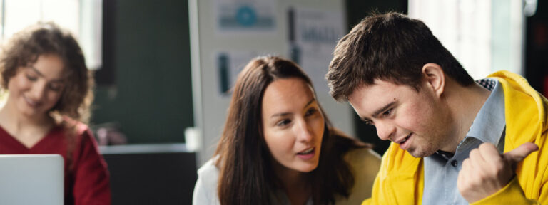 A young man with Down syndrome engaged in learning with a supportive tutor.