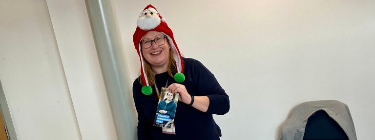 Woman in festive Santa hat smiling in an office environment
