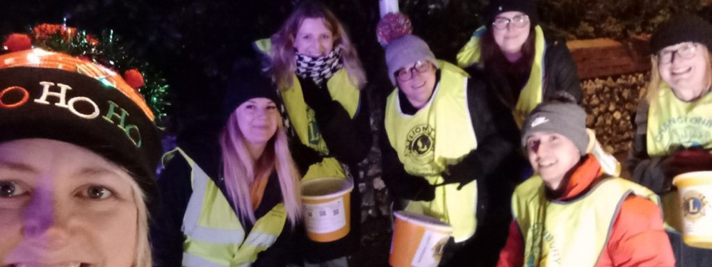 Group of volunteers in high-visibility jackets smiling during a night-time charity event
