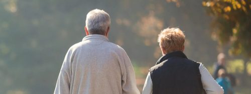 An elderly couple walking together in a park.
