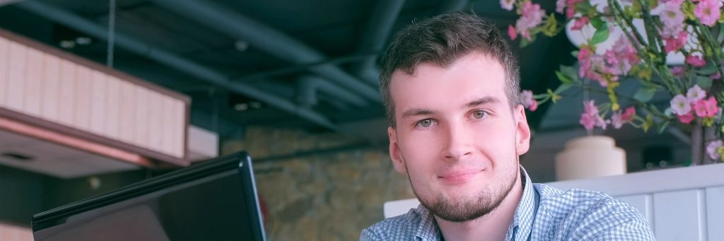 Young professional man with a pleasant expression sitting in a modern workspace.