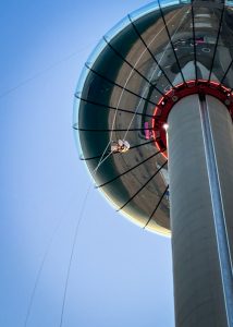 Person zip-lining from a high tower under a clear blue sky