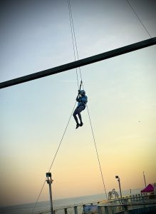 Adventurous individual zip-lining against a sunset sky at an outdoor event