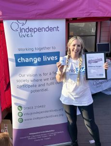 Happy volunteer Rebecca holding an award at an Independent Lives event.