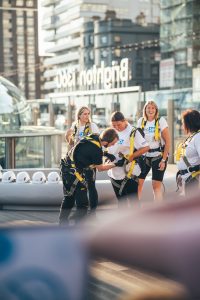 Participants in a charity event are assisted with safety gear in preparation for an activity.