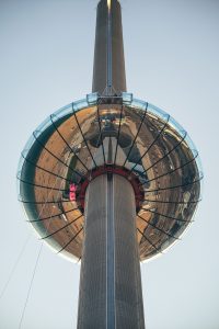 Looking up at the underside of a reflective observation deck on a tower with clear skies in the background.