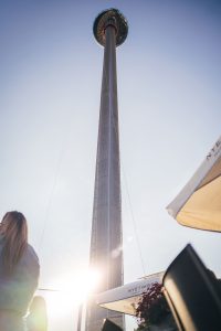 The sun sets behind a towering observation deck as onlookers gaze up from below.