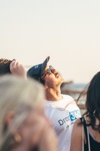 A man in a baseball cap looking upwards, wearing a t-shirt with the "Drop 360 Supporting Independent Lives" logo.