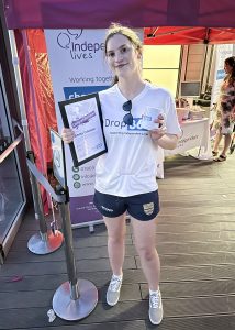 A woman holding a certificate and mug at an Independent Lives event