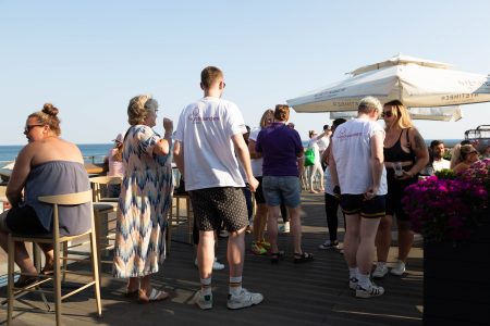 Attendees at an outdoor charity event by the seaside, wearing Independent Lives t-shirts.