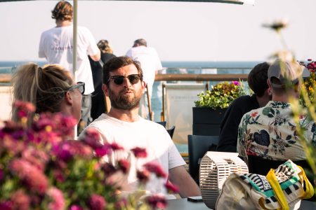 A man in sunglasses enjoying a sunny day at a charity event by the sea.