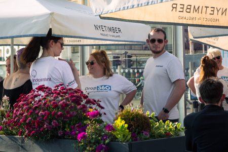 Volunteers from Independent Lives engaging with each other at a sunny outdoor charity event, surrounded by vibrant flowers.