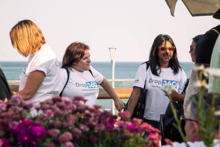 Volunteers from Independent Lives in conversation at a coastal event, with the ocean in the background.