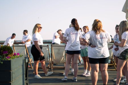 Volunteers wearing white shirts with Independent Lives logo enjoying a sunny day at an outdoor charity event.