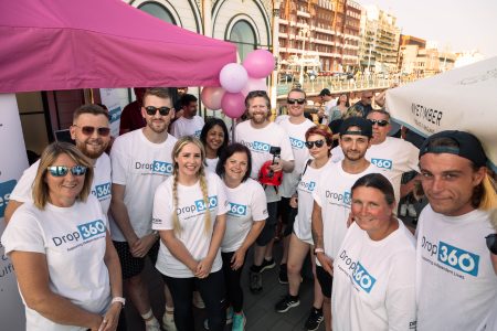 Group of cheerful people wearing Drop360 t-shirts at an Independent Lives charity event.