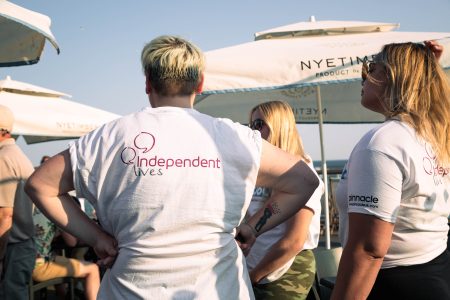 Individuals in white t-shirts printed with the "Independent Lives" logo at an outdoor social event.