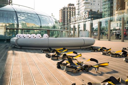 Safety gear including helmets and harnesses laid out on wooden decking, prepped for an outdoor abseiling activity.