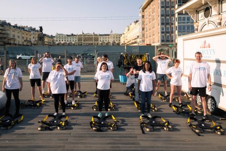 A group of enthusiastic participants in white Drop 360 t-shirts and yellow harnesses ready for an abseiling event.