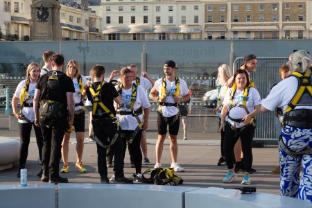 A group of enthusiastic participants in safety harnesses gear up for an urban outdoor adventure activity.