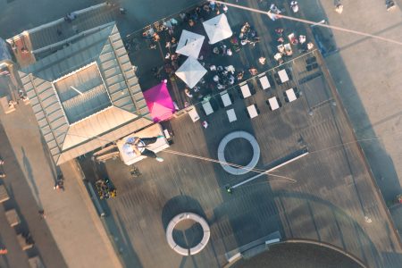 Aerial view of a charity abseil participant descending towards a rooftop event space at sunset.