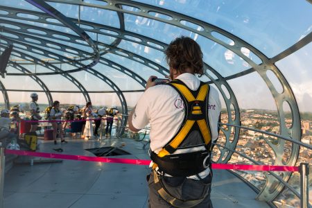 A participant in a harness observing a charity abseil event from within a futuristic glass dome structure.