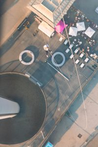Aerial view of a charity abseil participant descending towards a rooftop event space at sunset.