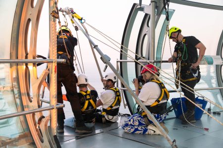 Abseiling instructors setting up equipment for a high-altitude charity event with participants looking on.