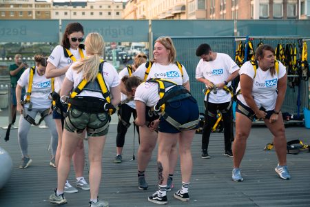 Group of individuals in safety harnesses preparing for a charity abseil event.