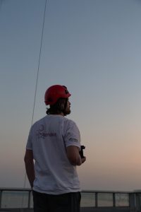 Man in red helmet holding a camera, looking up at the sky during twilight