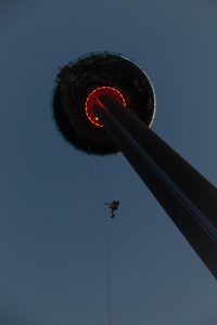 Adventurous individual descending on a zip line from the Brighton i360 during twilight.