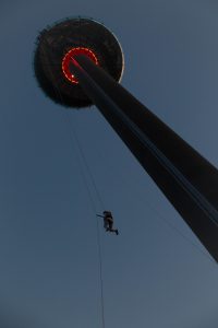 Adventurous individual descending on a zip line from the Brighton i360 during twilight.