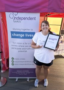 Lauren holds a certificate and a mug at the Independent Lives Drop 360 event