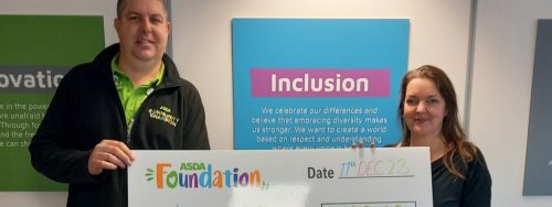 Rebecca Smicle, CEO of Independent Lives receives grant from ASDA Foundation holding a cheque with the word 'Inclusion' in the background.