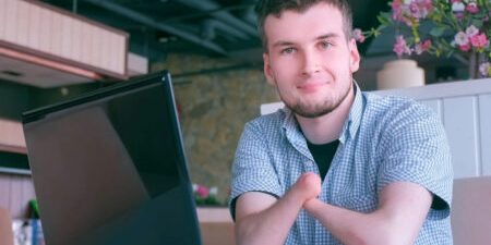 Confident young man with a laptop at a cafe