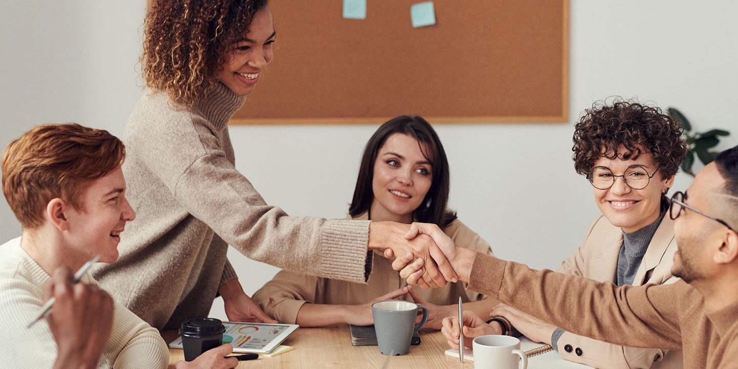 Diverse group of colleagues engaging in a handshake at a team meeting.