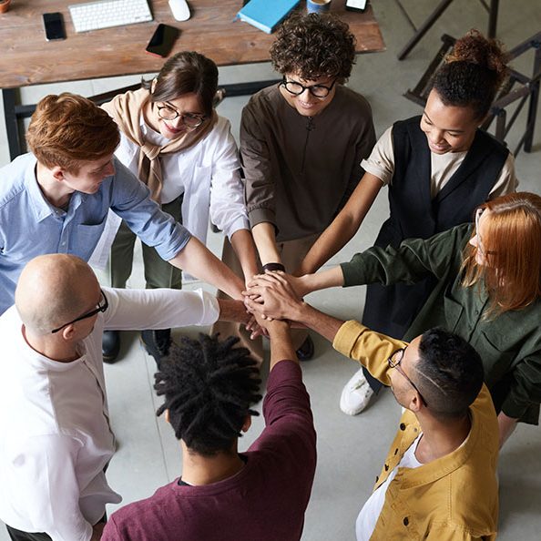 Diverse group of colleagues joining hands in a team-building exercise.