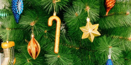 Close-up of a Christmas tree with sparkling ornaments including a cane, a star, and pinecones.