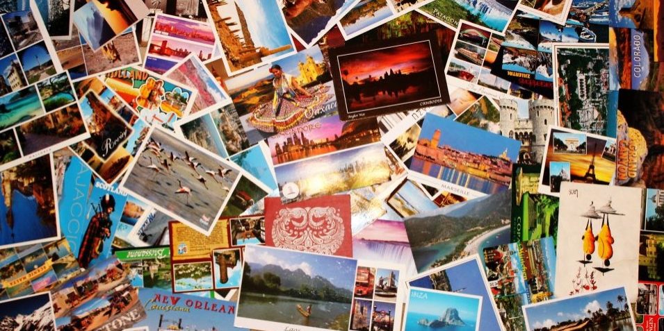 A collage of various colourful postcards from around the world spread out on a surface.