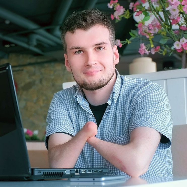 Confident young man with a laptop at a cafe