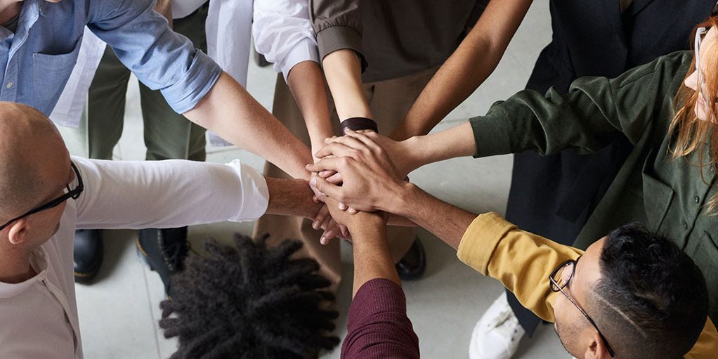 Diverse group of colleagues joining hands in a team-building exercise.